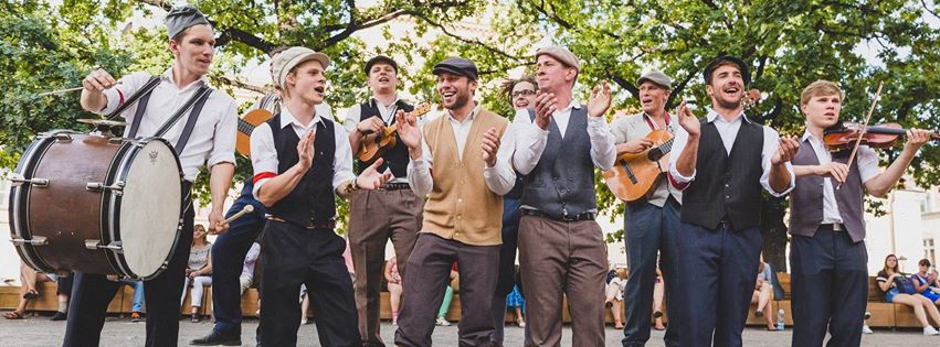 : A group of laughing musicians during an artistic performance in an urban space
