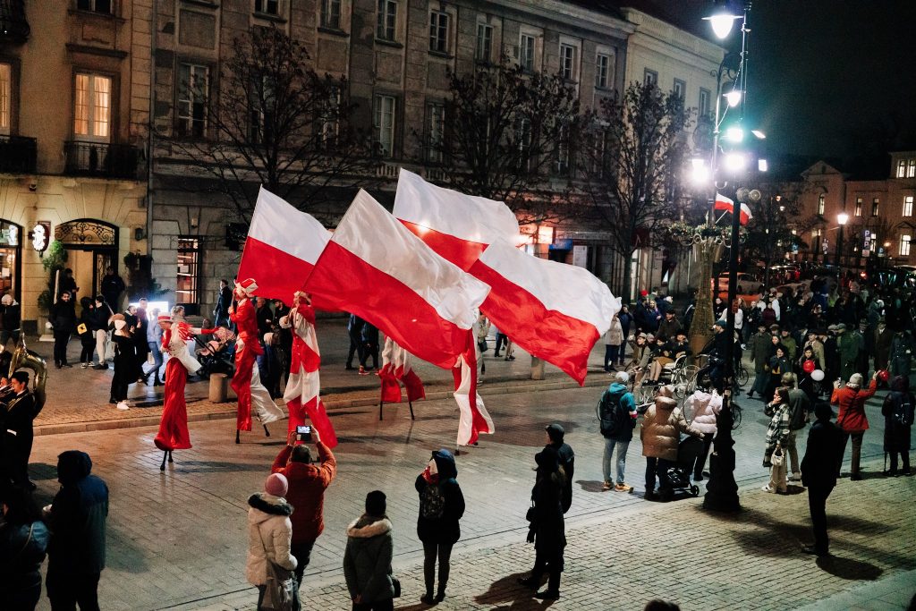 grupa z biało-czerwonymi flagami paraduje po ulicy