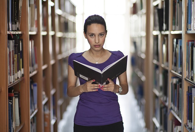 dziewczyna z książką, stojąca w bibliotece