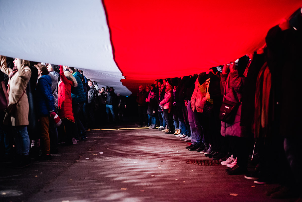 grupa ludzi trzymająca 100-metrową flagę Polski