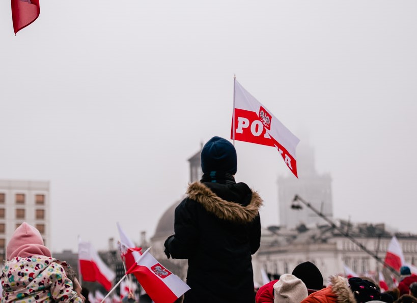 chłopczyk na czyichś ramionach niesie a'la flagę Polski