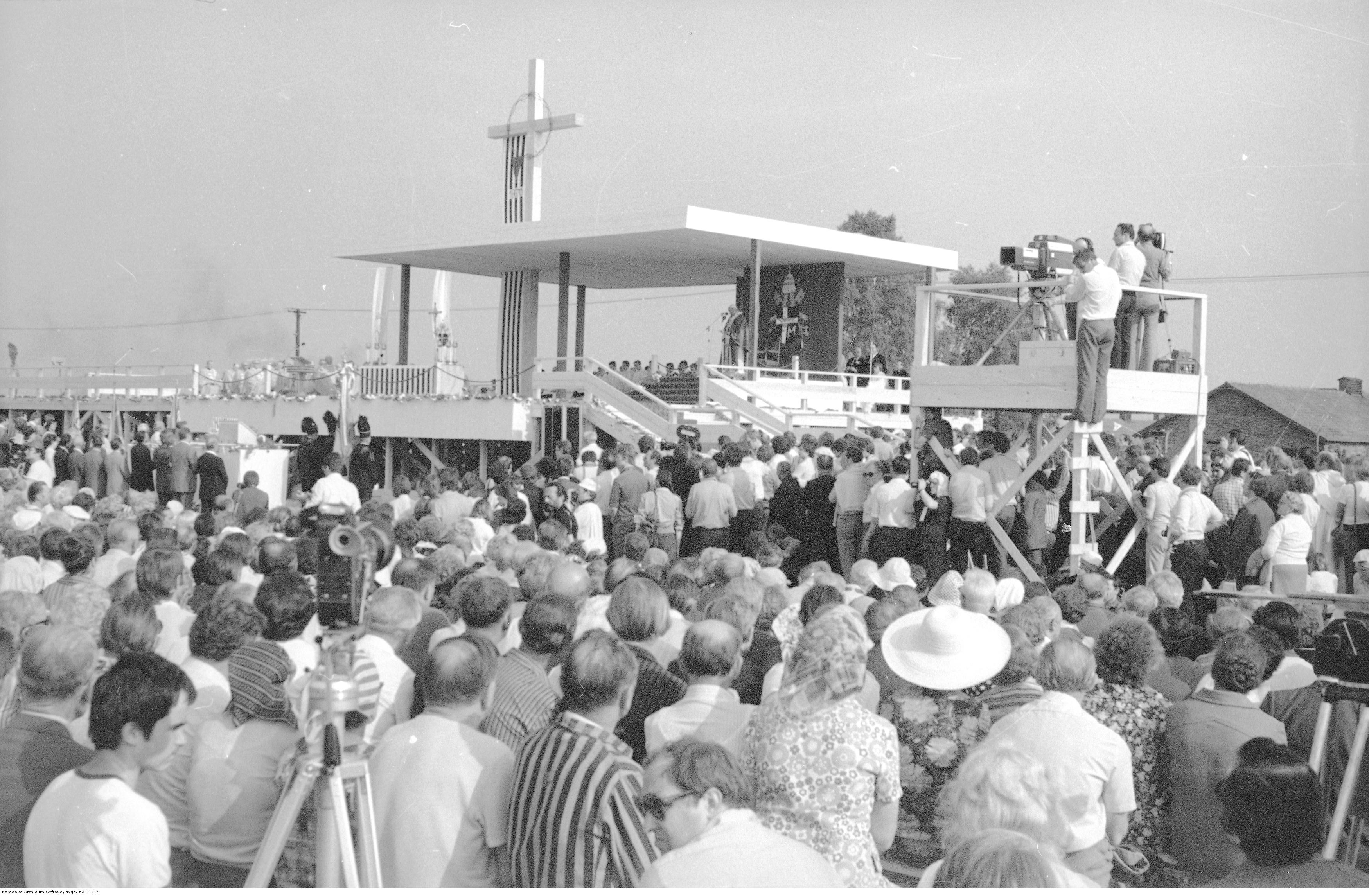 W centrum widoczny ołtarz, przy tronie papieskim widoczny Jan Paweł II, z prawej - stanowiska operatorów kamer, cała przestrzeń jest wypełniona ludźmi przybyłymi na spotkanie.