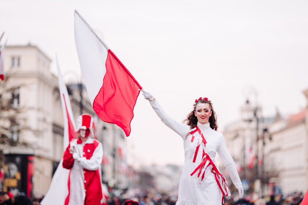kobieta na szczudłach z biało-czerwoną flagą