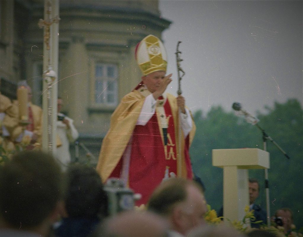 Papież Jan Paweł II błogosławi wiernych przed rozpoczęciem mszy św. jubileuszowej z okazji sześćsetlecia klasztoru na Jasnej Górze. Na dalszym planie widoczni biskupi oraz fragment klasztoru.