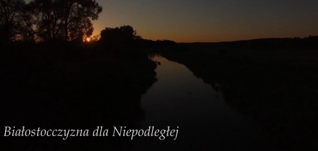 widoczek zachodzącego słońca nad rzeką wśród łąk, w dole tytuł cyklu reportaży