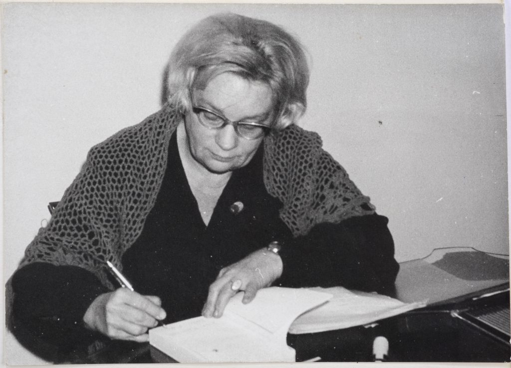 starsza kobieta podpisująca książkę