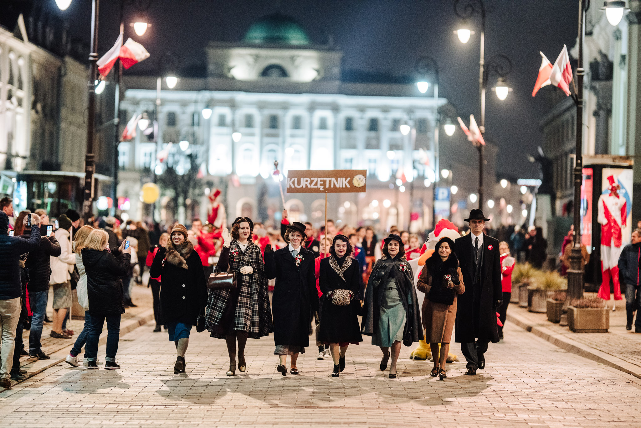 alpaka wikunia ludzie idący po krakowskim przedmieściu w paradzie, na pierwszym planie rekonstruktorki międzywojenne