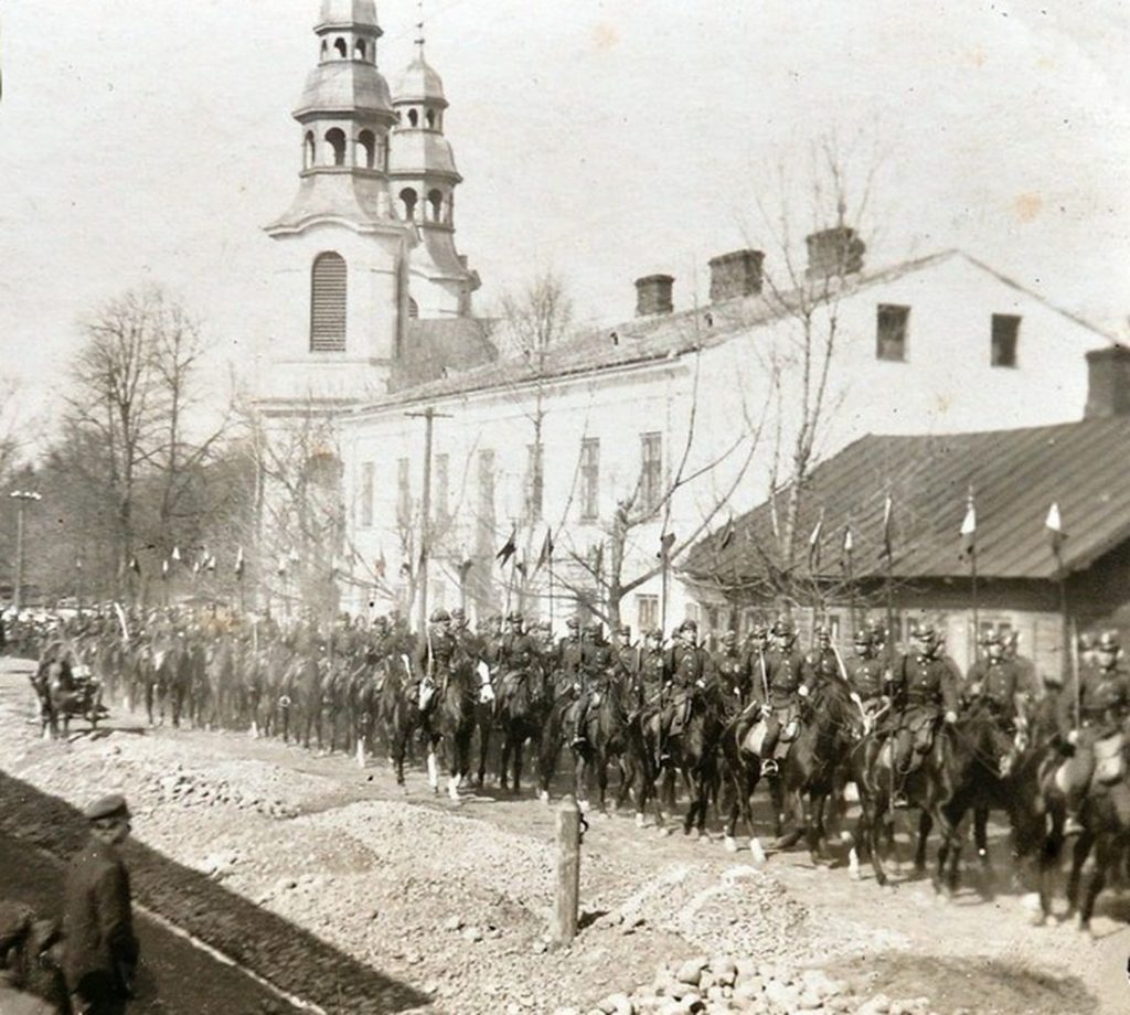 historyczne zdjęcie żołnierzy maszerujących w kolumnie przy kościele