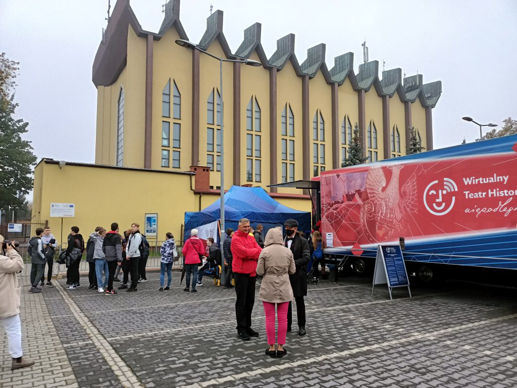 Ciężarówka z Wirtualnym Teatrem Historii Niepodległa stojąca w wołominie. W tle kościół św. Józefa robotnika