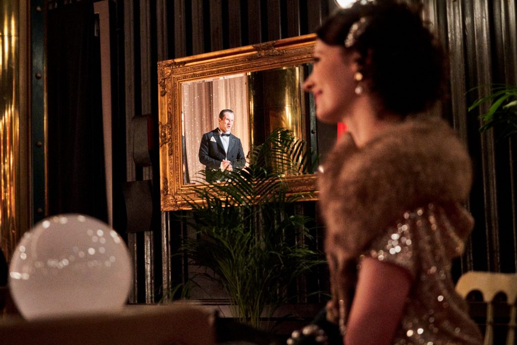 kobieta z uśmiechem patrzy na scenę, w lustrze odbija się mężczyzna ze sceny