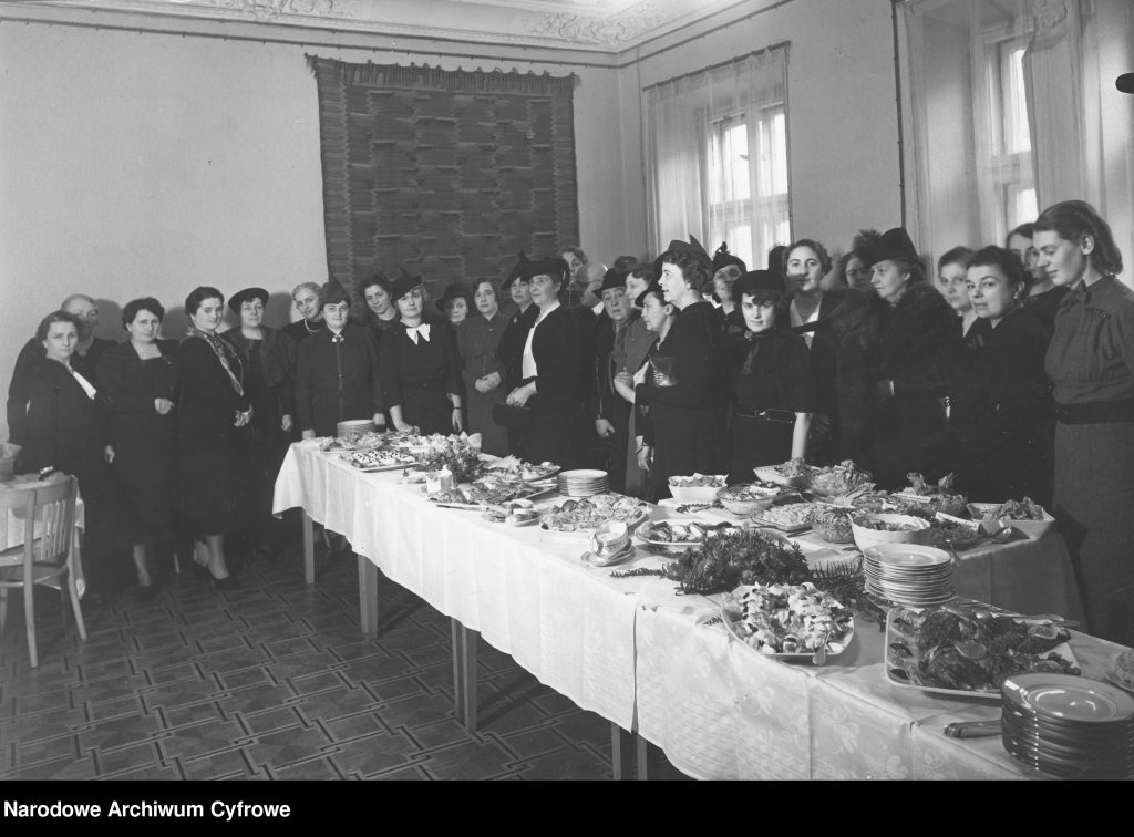 kobiety zgromadzone przy długim stole gęsto zastawionym jedzeniem