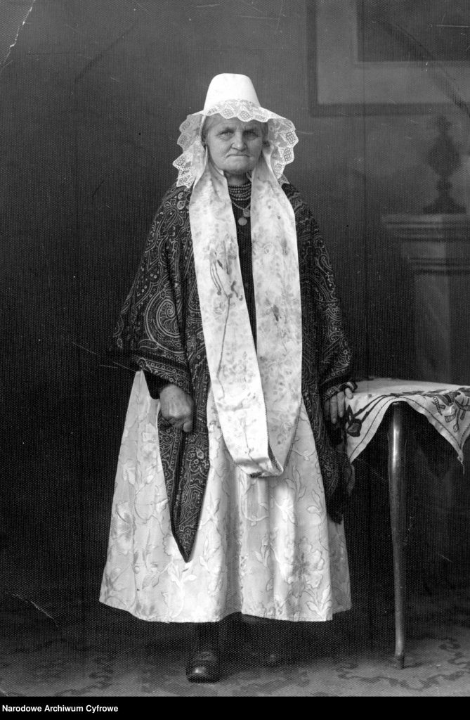 starsza kobieta stoi na zdjęciu portretowym w stroju ludowym