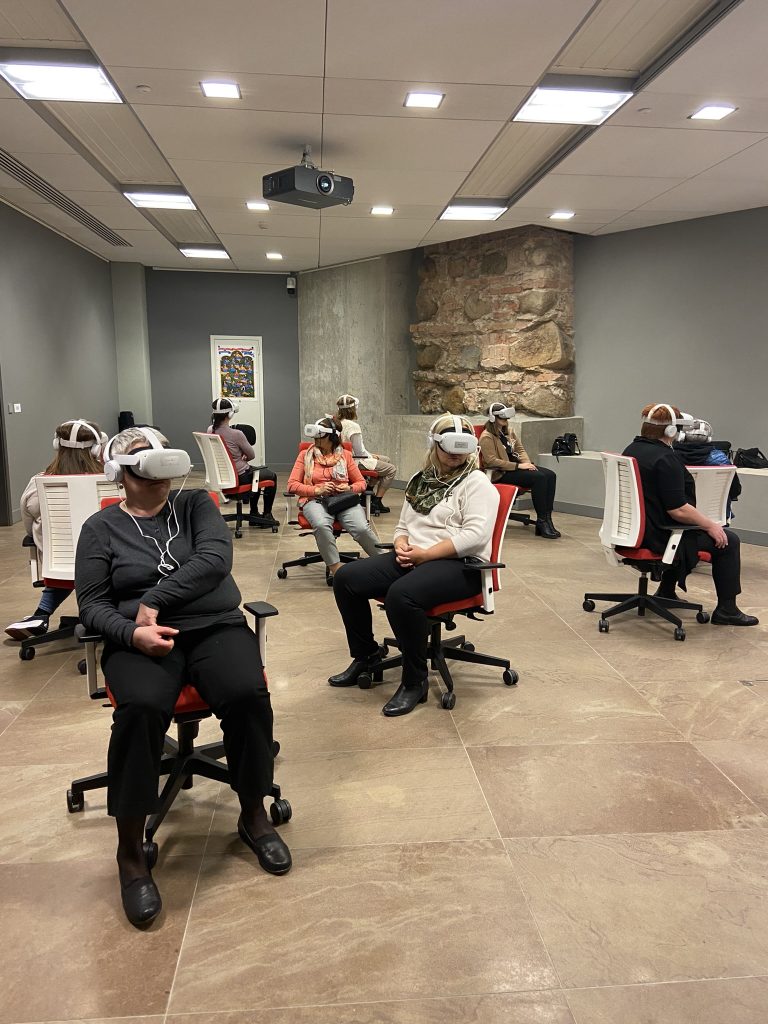 ludzie w czasie pokazów VR siedzący na krzesłach obrotowych - każdy zwrócony w inną stronę