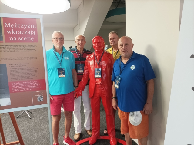 czterech mężczyzn pozujących przy czerwonej rzeźbie stojącego mężczyzny