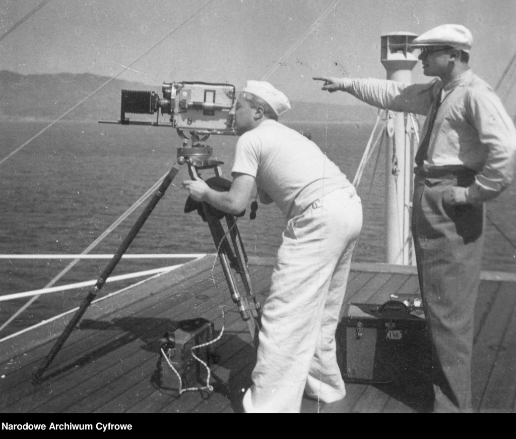Ekipa filmująca wybrzeża podczas rejsu "Piłsudskiego". Widoczna rozstawiona na statywie kamera oraz operator. 