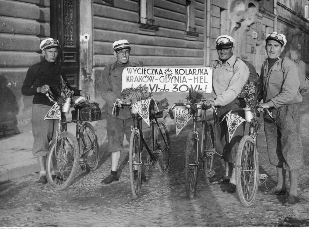 czterech mężczyzn na rowerach pozuje z transparentem ze swoją trasą