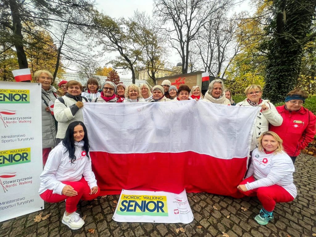 seniorki na warsztatach nordic walking pozują do zdjęcia z biało-czerwoną flagą