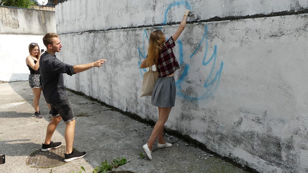 Zdjęcie przedstawia tworzenie Muralu przez młodzież 