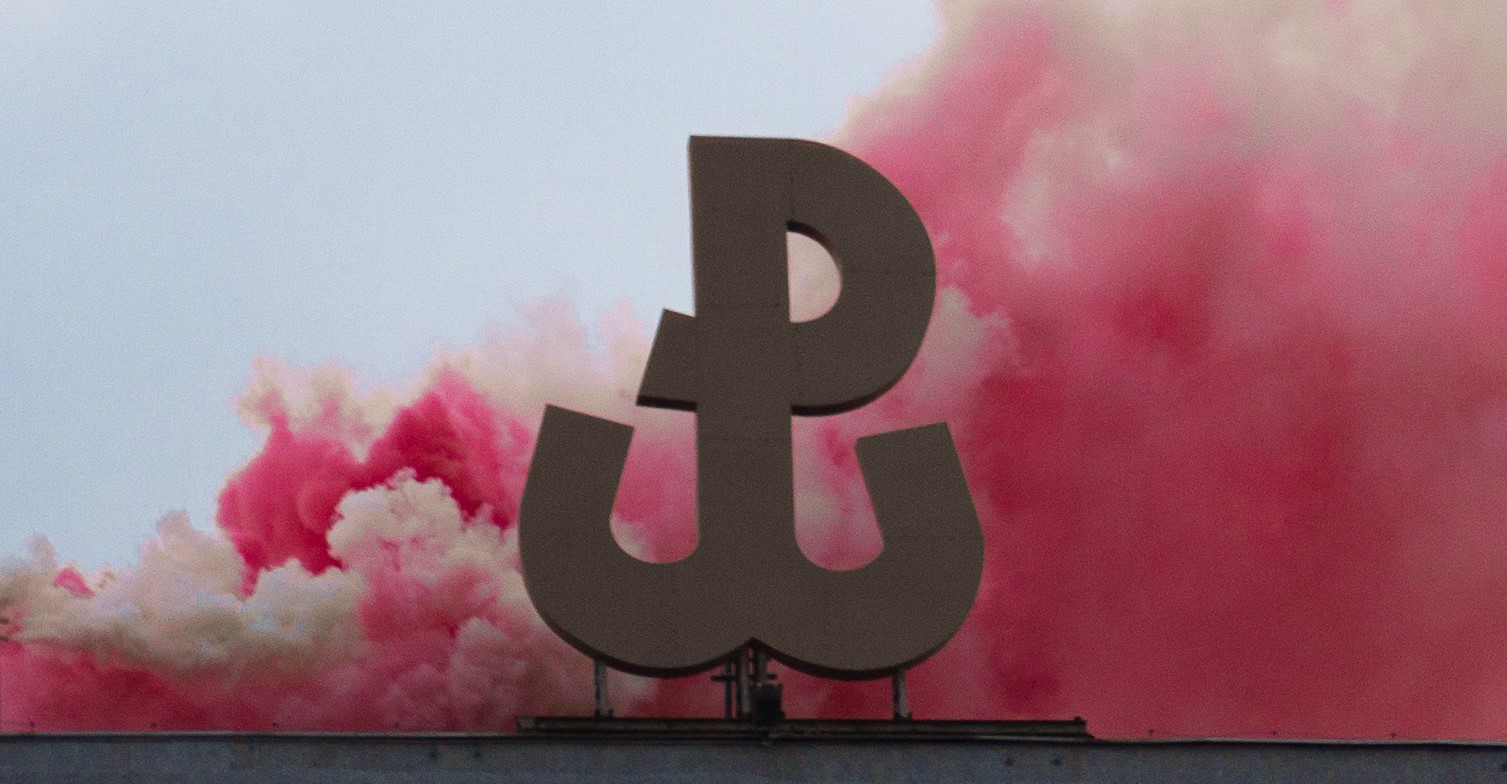 znak Polski Walczącej na tle biało-czerwonego dymu
