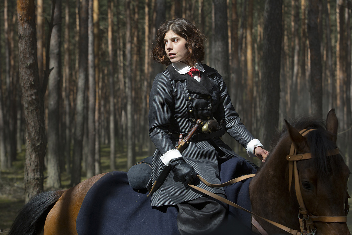 fotos z planu pokazujcy kobietę w dawnym stroju na koniu