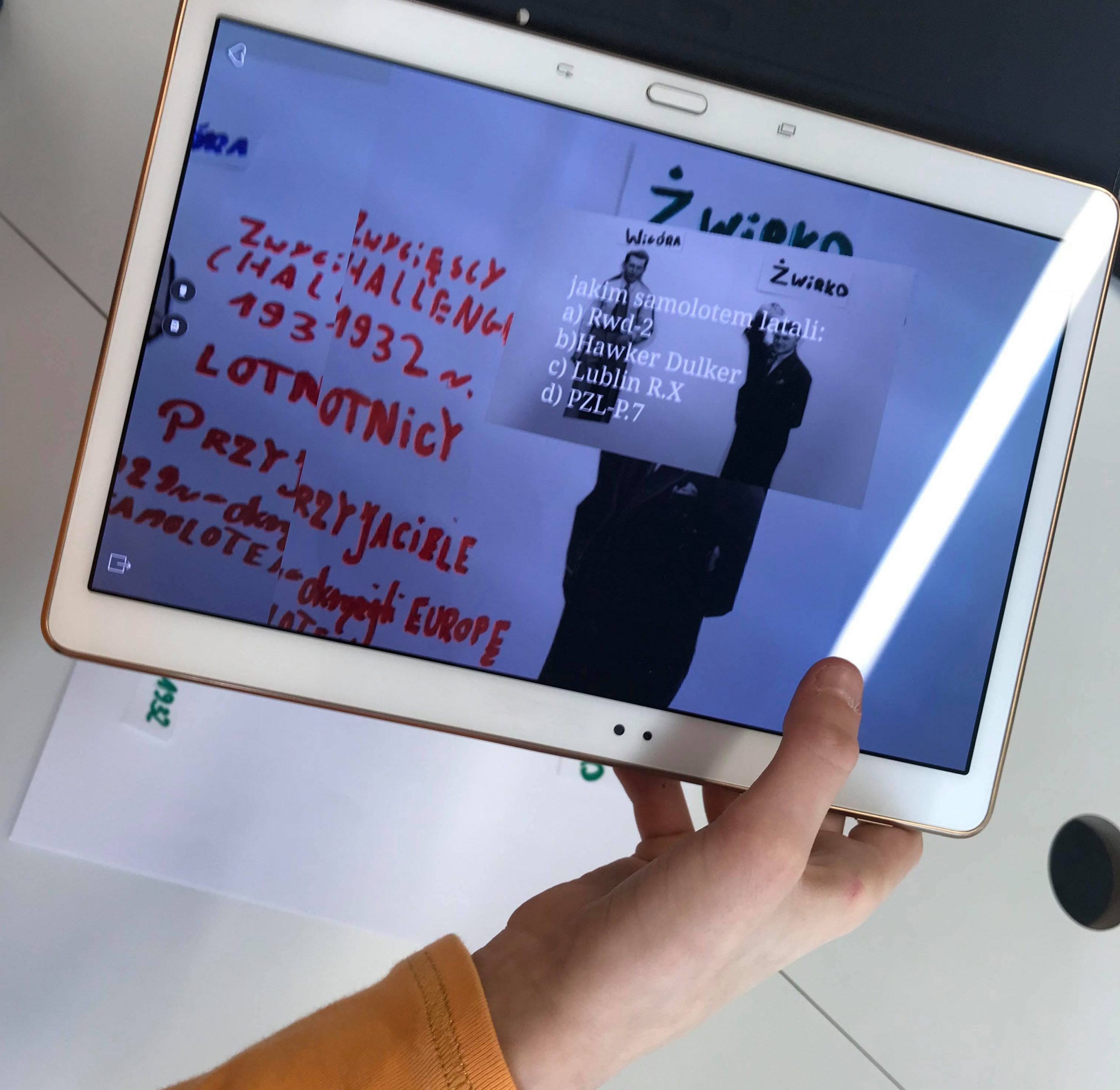 tablet w dłoni z ekranem z wykonanym zadaniem z warsztatów